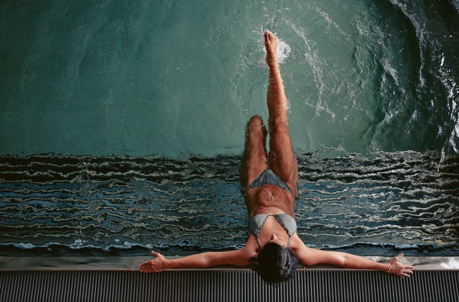 Frau sitzt auf der Whirlbank im Schwimmbad