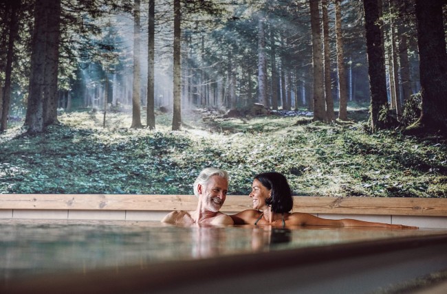 Paar auf der Whirlbank mit Massagedüsen im Hallenbad